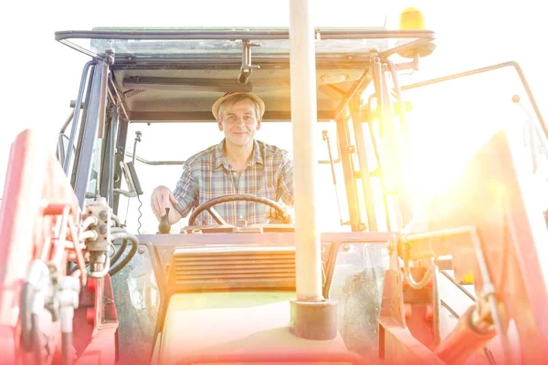 confident farmer driving tractor at farm