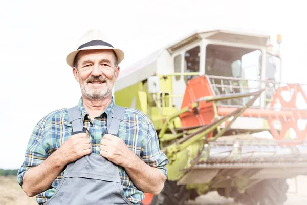 農場トラクターに対して立っている自信の上級農民の肖像画 — ストック写真