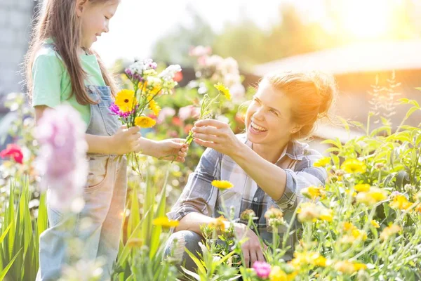 Usměvavá Matka Dává Květiny Dceři Zatímco Zahraduje Farmě — Stock fotografie