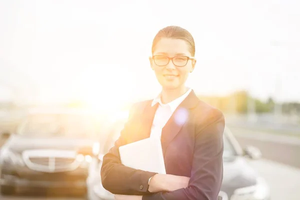 若い魅力的なビジネスマン黄色のレンズフレアと道路の真ん中に車に対して立っている女性 — ストック写真