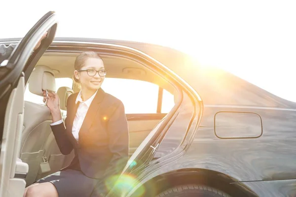 若い魅力的なビジネス女性が背景に黄色のレンズフレアで車を降りる — ストック写真