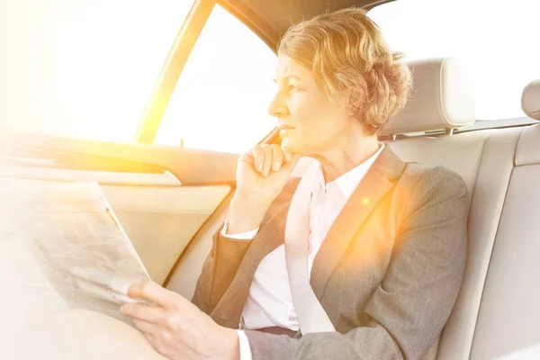 Businesswoman Talking Smartphone While Reading Newspaper Car Yellow Lens Flare — Stock Photo, Image