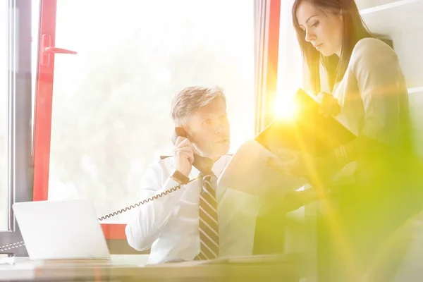 Secretaris Toont Document Terwijl Zijn Manager Telefoneert Met Gele Lensflare — Stockfoto