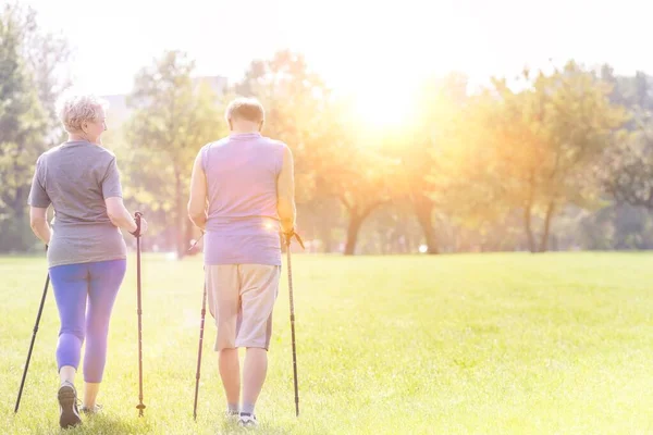 back view of Senior couple with hiking poles walking outdoors