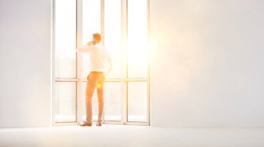 Yeni ofiste akıllı telefonda konuşan genç işadamının tam uzunlukta arka görünümü