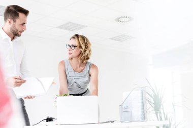 Genç çekici iş adamı iş kadınıyla ofiste iş planlarını tartışıyor.