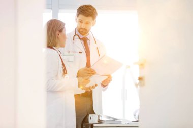 Hastanedeki hastanın tıbbi sonuçlarını mercekle tartışan olgun doktorların portresi 