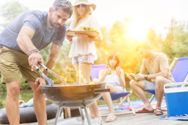 Adam, kız arkadaşı ve arkadaşlarıyla gölde ızgara yaparken Tong kullanıyor.