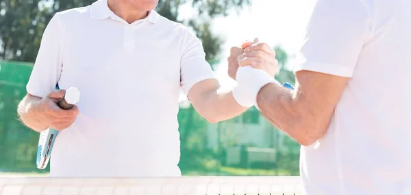成熟した選手がテニスコートで握手でお互いを迎える — ストック写真