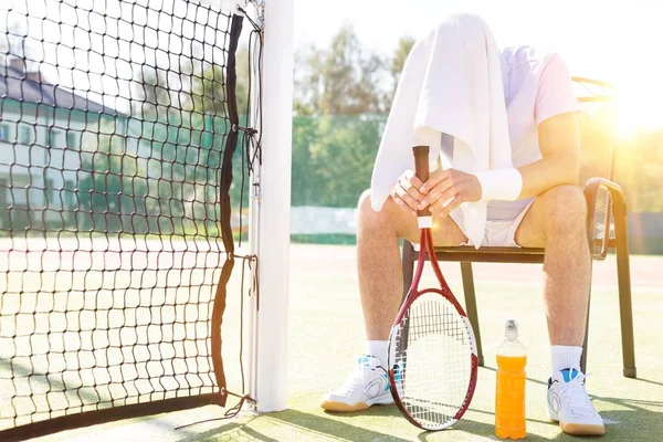 精疲力竭的男子在球场上打网球后 坐在那里休息和擦汗 背带黄色镜头照明弹 — 图库照片