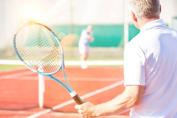 在球场上打网球的成熟运动员近视 背景为黄色镜头照明弹 — 图库照片