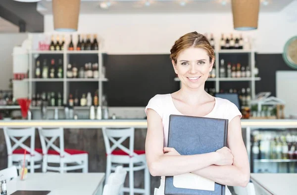 Retrato Jovem Garçonete Sorrindo Segurando Menu Enquanto Está Restaurante — Fotografia de Stock