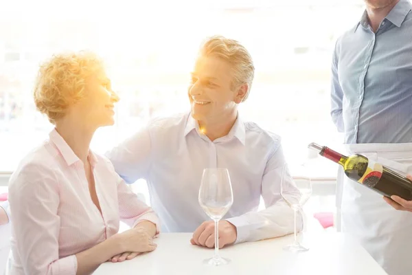 Foto Casal Sênior Sentado Enquanto Garçom Derramando Vinho Tinto Seus — Fotografia de Stock