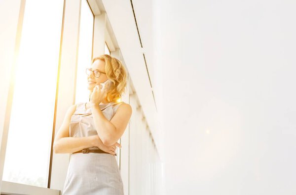 Зрелая бизнесвумен разговаривает по смартфону с желтыми линзами на заднем плане 