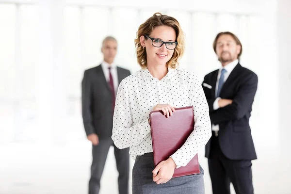 新しい空のオフィスで同僚に対する文書を保持しながら立って若い美しい実業家の肖像 — ストック写真