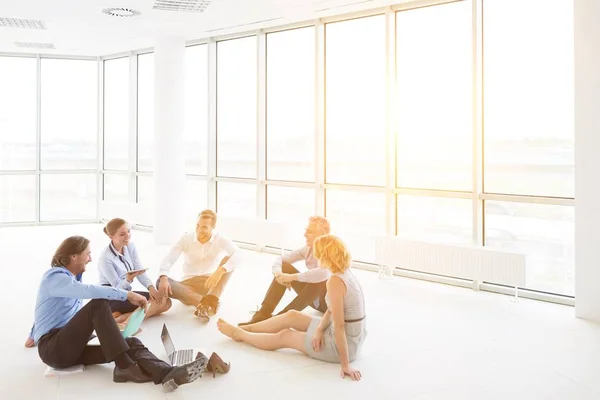 Obchodní Kolegové Diskutovat Zatímco Sedí Podlaze Proti Oknu Nové Kanceláři — Stock fotografie