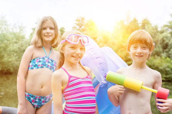 Портрет детей в купальниках на озере с желтыми линзами на заднем плане