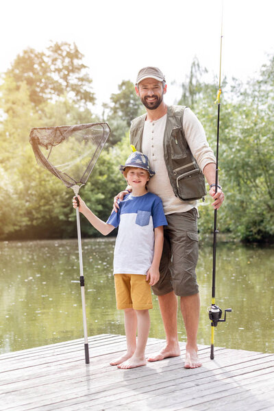Father and son fishing in Lake while sitting on pier
