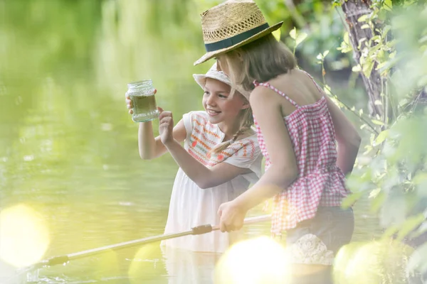 湖に立ちながら瓶を見ている笑顔の女の子 — ストック写真