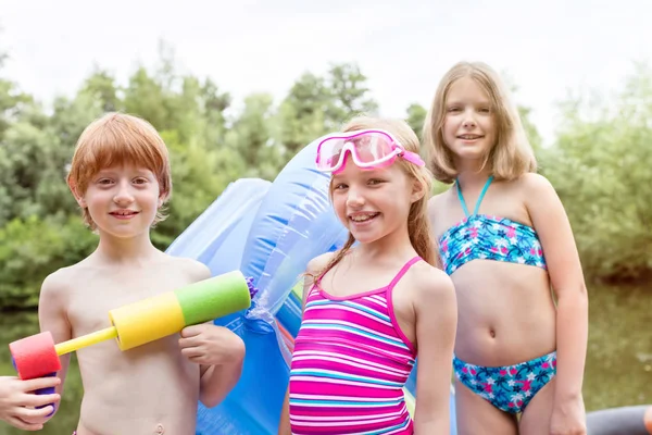 Portrait Smiling Friends Swimwear Standing Pool Raft Squirt Gun Lakeshore — Stock Photo, Image