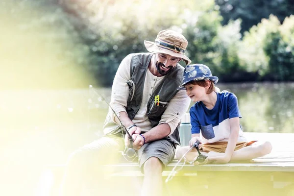 Father and son fishing in Lake while sitting on pier