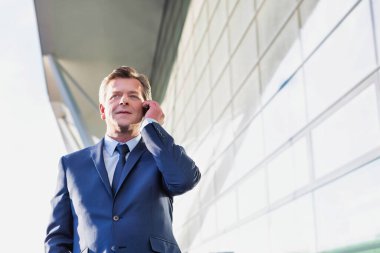 Gdansk Havaalanı 'nda dikilirken akıllı telefondan konuşan olgun çekici iş adamının portresi