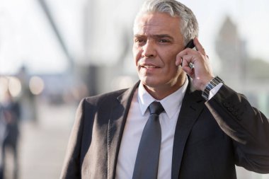 Olgun iş adamı havaalanında akıllı telefondan konuşuyor.
