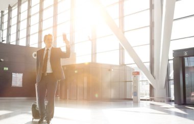 Çekici, olgun iş adamı havaalanında yolcu alımı için kapıdan giriyor.