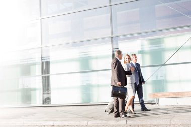 İş adamları havaalanında yürürken konuşuyor.