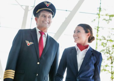 Uçuş görevlileriyle birlikte havaalanında yürüyen bir pilot.