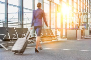 Havaalanında yürüyen genç uçuş görevlisinin kamera arkası görüntüsü.