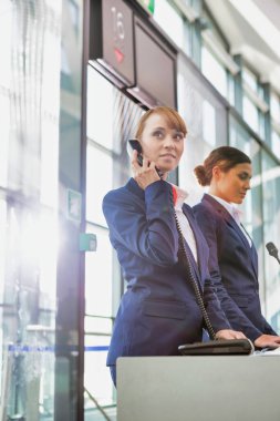 Havaalanı kapısında dikilirken telefonla konuşan çekici genç bir yolcunun portresi.
