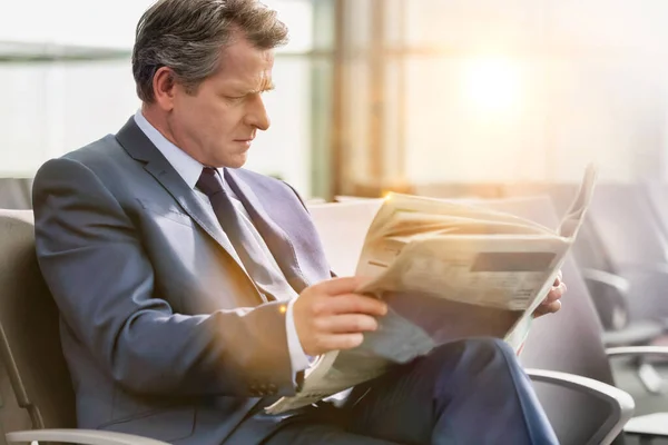 Ώριμος Επιχειρηματίας Που Κάθεται Και Διαβάζει Εφημερίδα Ενώ Περιμένει Επιβίβαση — Φωτογραφία Αρχείου