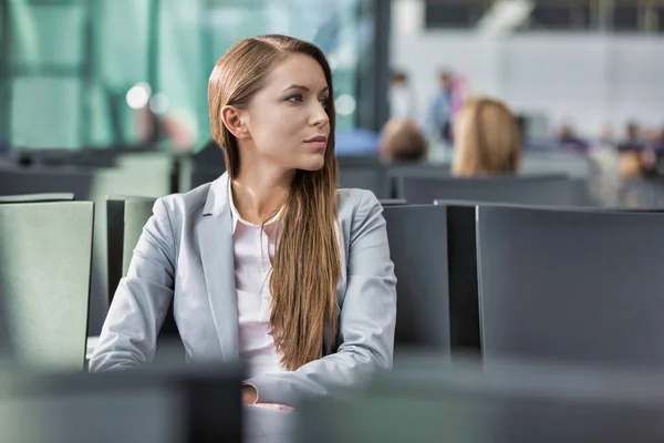 年轻迷人的女商人坐在大门口等待机场登机时的画像 — 图库照片