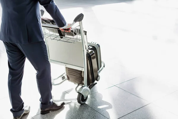 成熟したビジネスマン空港でのチェックインのための荷物カートを押す — ストック写真