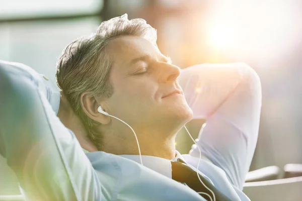 Mature Businessman Sleeping While Listening Music Earphones Airport Lens Flare — Stock Photo, Image