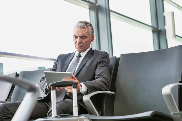Olgun Adamı Otururken Havaalanının Kapısında Beklerken Dijital Tablet Kullanıyor — Stok fotoğraf
