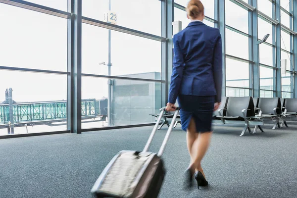 レンズフレア付き空港内を歩く若い客室乗務員の背面図 — ストック写真