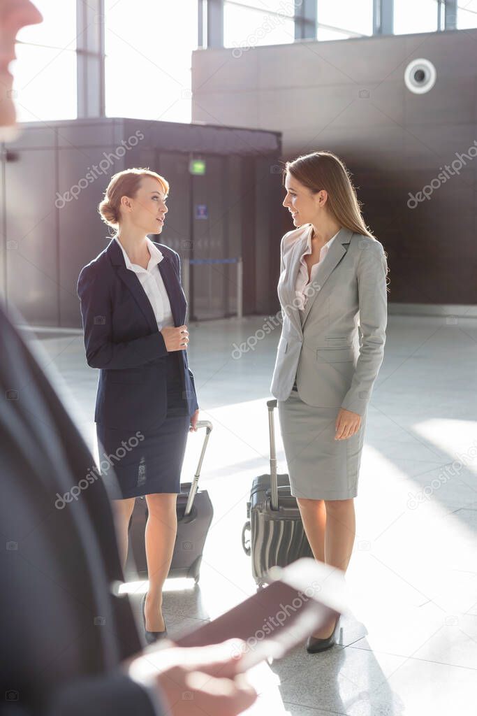 Businesswomen discussing plans while walking with their suitcase in airport