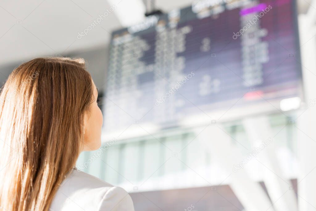 Businesswoman looking at flights display screen in airport