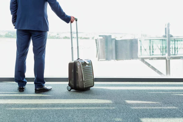 空港の窓を通して見ている間 彼のスーツケースと一緒に立って成熟したビジネスマンの肖像画 — ストック写真