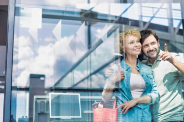 Havaalanındaki pencereden bakan olgun bir çiftin fotoğrafı.