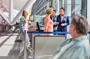 Olgun bir kadın havaalanında pasaportunu ve biniş kartını veriyor.