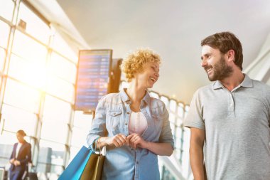 Havaalanında konuşurken yürüyen olgun bir çiftin portresi.