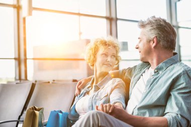 Olgun çift havaalanında uçmayı beklerken oturuyorlar.