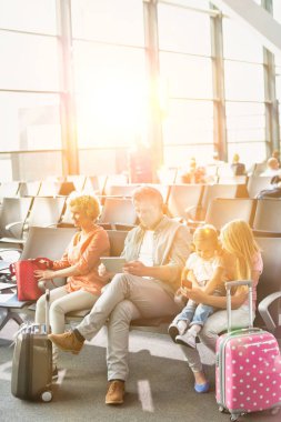 Olgun adam havaalanında oturup beklerken dijital tablet kullanıyor.