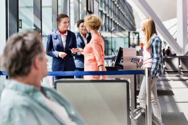 Olgun bir kadın havaalanında pasaportunu ve biniş kartını veriyor.