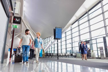 Havaalanında konuşurken yürüyen olgun bir çiftin portresi.