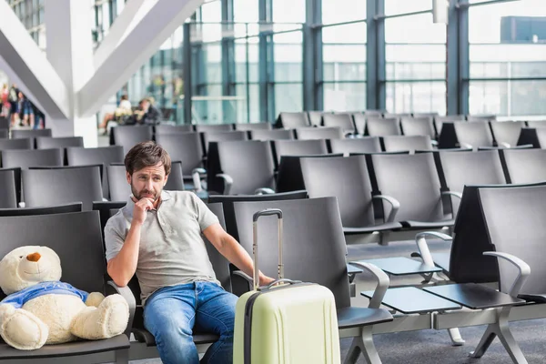 男子与泰迪熊和西服盒坐在机场等待登机的肖像 — 图库照片