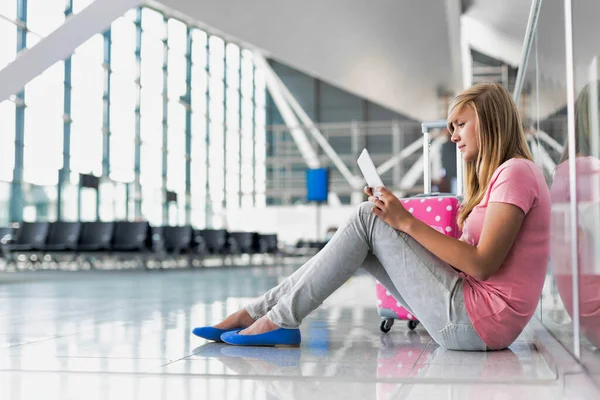 若い十代の少女の肖像画は 床に座って 空港で彼女の飛行を待っている間 デジタルタブレットを使用して — ストック写真